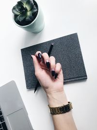 Cropped image of woman showing painted fingernails on table