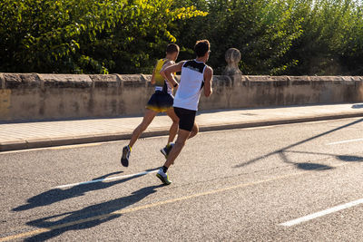 Rear view of men running on road