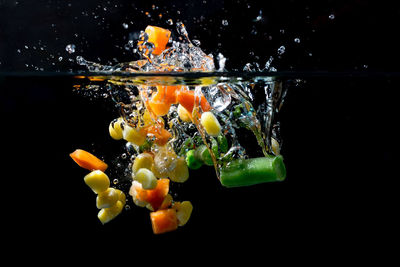 Close-up of vegetables falling in water against black background