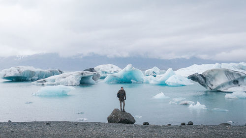 Full length of man standing on frozen lake against sky