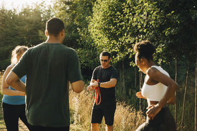 Fitness instructor training male and female athletes while exercising in park