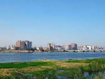 Sea by buildings against clear blue sky