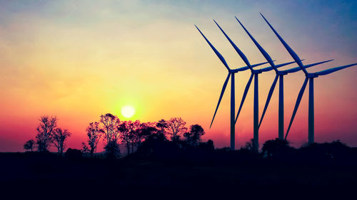 Silhouette of wind turbines against sky during sunset