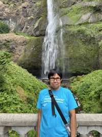 Rear view of woman standing against waterfall