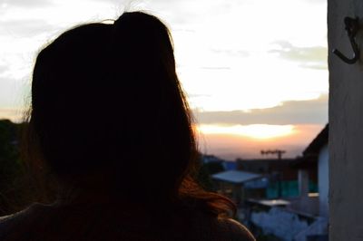 Rear view of woman standing against sky during sunset