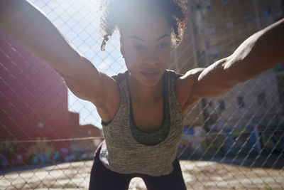 Sportswoman stretching while exercising in front of fence