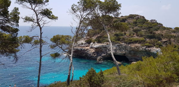 Scenic view of rocks by sea against sky