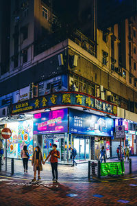 People walking on illuminated street at night