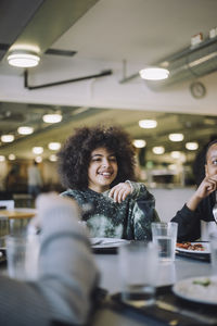 Smiling girl with curly hair sitting at table during lunch break at school