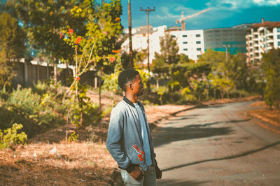 Side view of man standing against plants in city