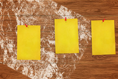 Close-up of yellow papers against wooden wall