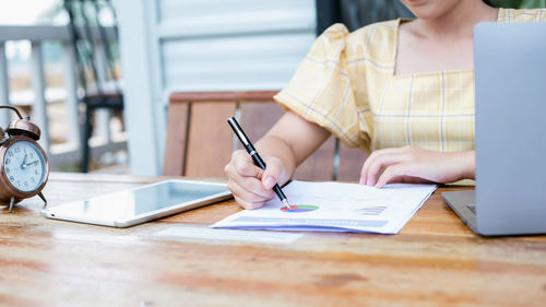 Midsection of woman reading book on table