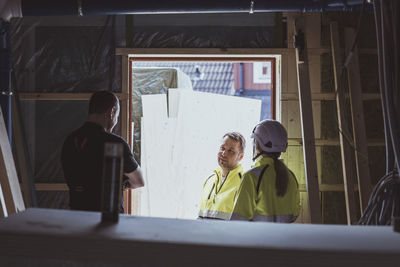 Male construction worker discussing with colleague and female building contractor at site