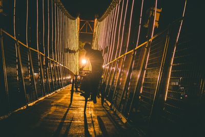 Man riding tricycle on footbridge at night