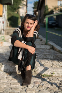 Full length portrait of young woman sitting on steps