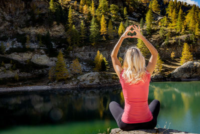 Rear view of woman with arms raised in lake