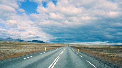 Country road against cloudy sky