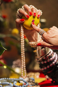 Cropped hands of woman wearing jewelry holding orange