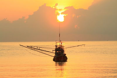 Silhouette sailboat in sea against sky during sunset