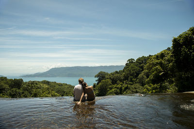 Couple sitting by the waterfall and looking at sea