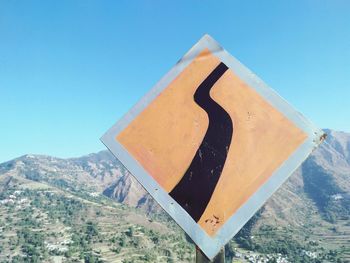 Information sign on mountain against clear blue sky