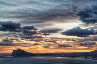 Scenic view of sea against dramatic sky during sunset