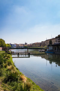 Bridge over river by buildings in city against sky