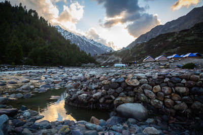 Rocks by river against sky