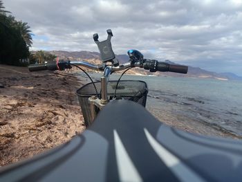 Bicycle on road by sea against sky