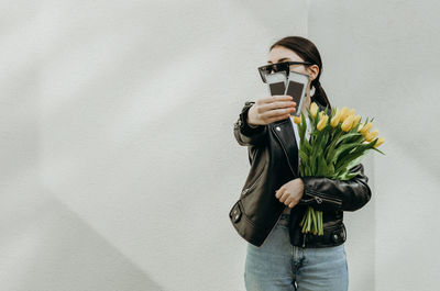 A girl with tulips holds out a package of eyelashes for extensions.