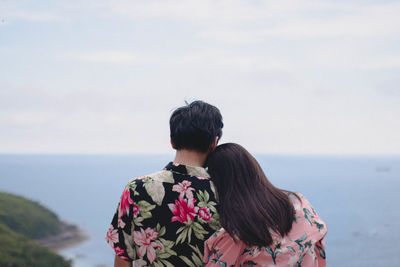 Rear view of couple looking at sea against sky