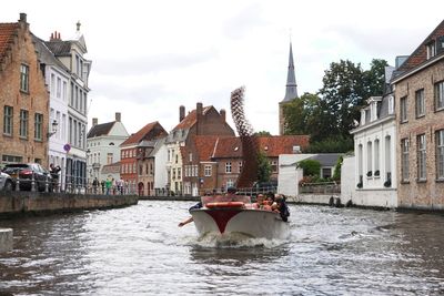 Boats sailing in canal amidst buildings in city