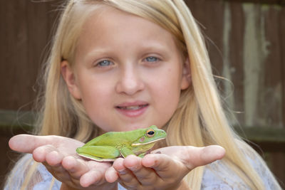 Close-up portrait of smiling girl holding leaf