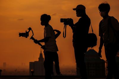Rear view of silhouette friends standing against sky during sunset in jakarta 