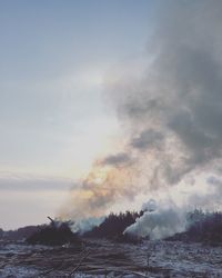 Smoke emitting from bonfires burning on field against sky during sunset during winter