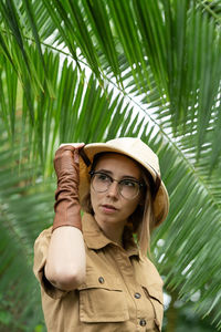 Portrait of woman standing by palm tree