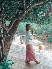 Side view of woman walking against plants in park