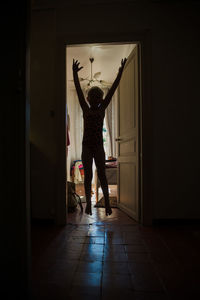 Girl jumping in doorway at home