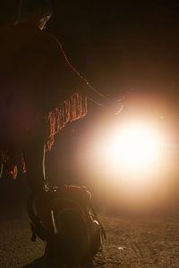 Side view of unrecognizable female hitchhiker standing on dark road and catching car at night during vacation