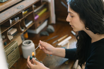 Female jewler working over flame with wax at home studio desk space