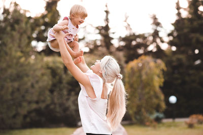 Happy mother picking up daughter at park