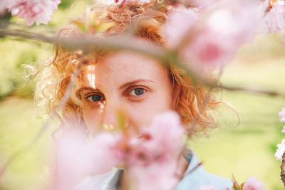 Close-up portrait of beautiful woman by blossoms in park