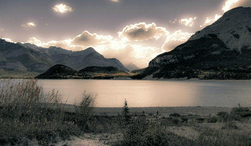 Scenic view of lake and mountains against sky at sunset