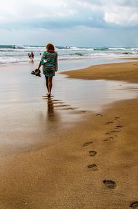 Full length rear view of woman walking on beach