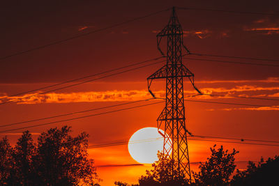 Low angle view of silhouette electricity pylon against sky during sunset