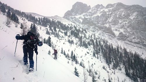 Rear view of hiker climbing snowcapped mountain