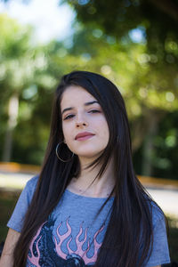 Portrait of young woman sitting on bench at park