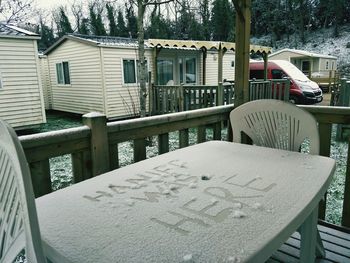 Chairs and tables in snow against buildings