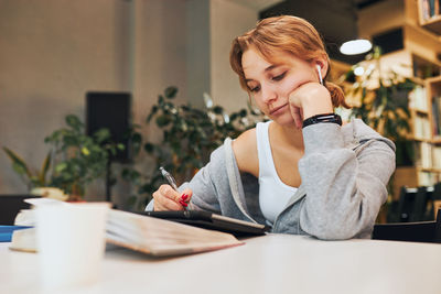 Young woman using mobile phone while sitting at home