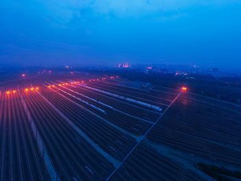 High angle view of illuminated city against blue sky